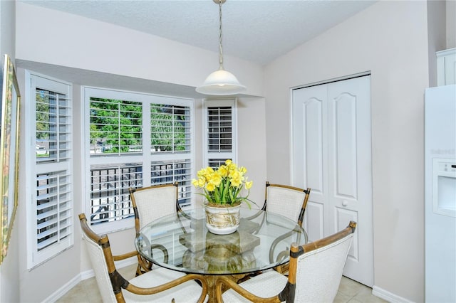 tiled dining room with lofted ceiling and a textured ceiling