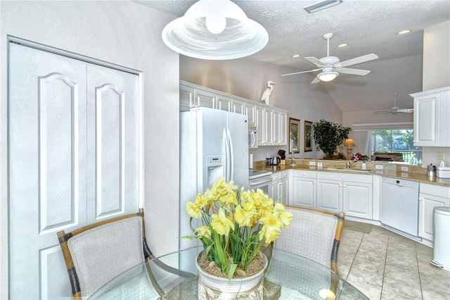 kitchen with lofted ceiling, white cabinets, kitchen peninsula, sink, and white appliances