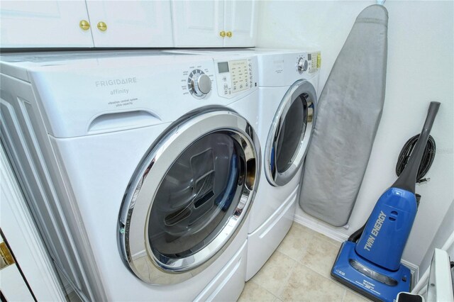 washroom with cabinets, washing machine and dryer, and light tile patterned floors