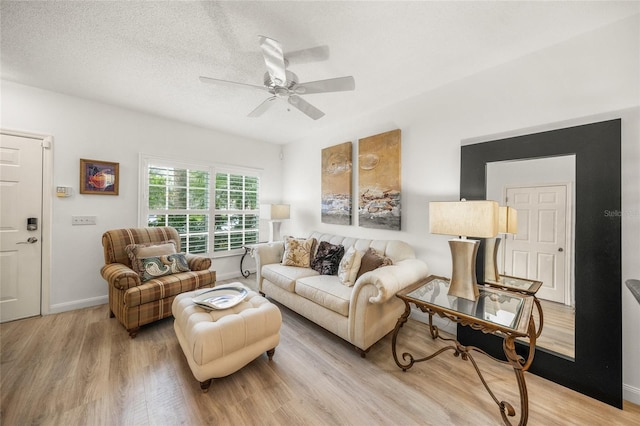 living room with a textured ceiling, light wood-type flooring, and ceiling fan