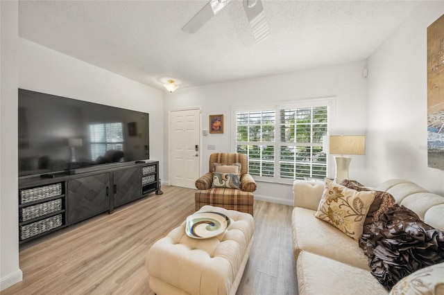 living room featuring ceiling fan, a textured ceiling, and light wood-type flooring