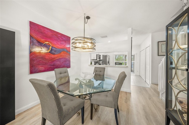 dining area featuring light hardwood / wood-style flooring and a notable chandelier