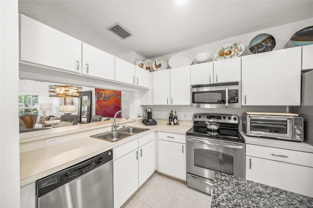 kitchen featuring a textured ceiling, sink, light tile patterned floors, white cabinetry, and appliances with stainless steel finishes