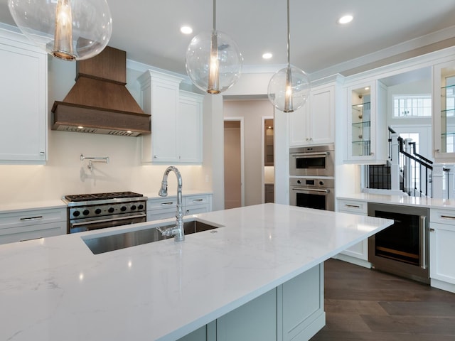 kitchen with pendant lighting, white cabinets, sink, appliances with stainless steel finishes, and beverage cooler