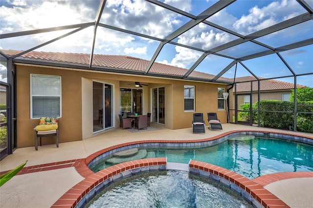 rear view of property with a lanai, a patio area, ceiling fan, and a swimming pool with hot tub