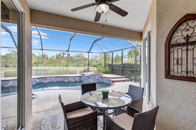 view of patio featuring a water view, glass enclosure, ceiling fan, and a pool with hot tub