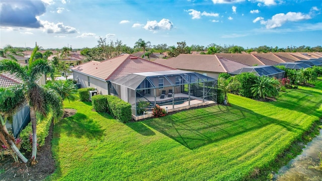 rear view of house featuring a lawn, glass enclosure, and a patio