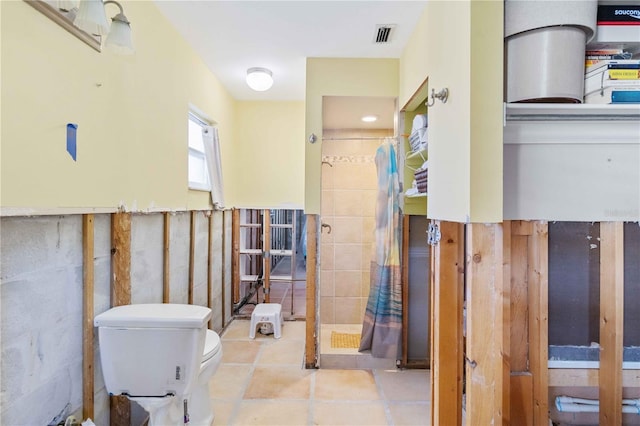 bathroom featuring tile patterned floors, toilet, and tile walls