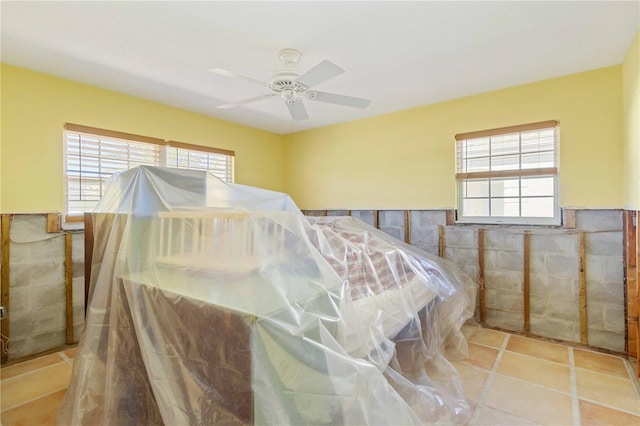 tiled bedroom with ceiling fan and tile walls