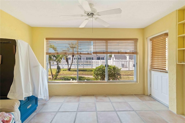 unfurnished sunroom featuring a wealth of natural light and ceiling fan