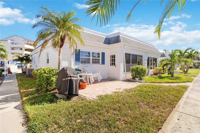 exterior space featuring cooling unit, a patio area, and a front yard