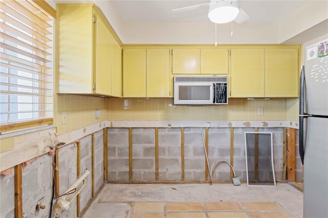 kitchen with tasteful backsplash, stainless steel refrigerator, and ceiling fan