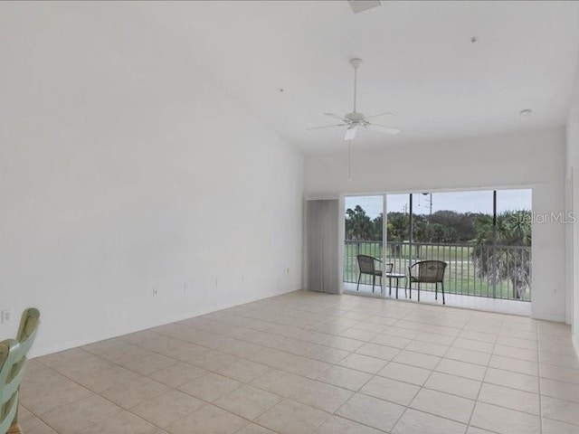 tiled empty room featuring ceiling fan and a high ceiling