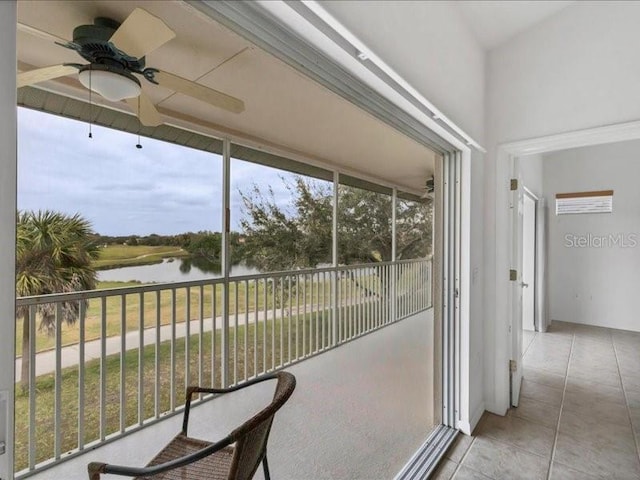 sunroom / solarium featuring ceiling fan and a water view