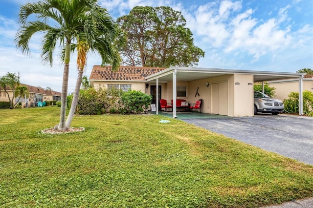 view of front of property featuring an attached carport, driveway, a front yard, and stucco siding