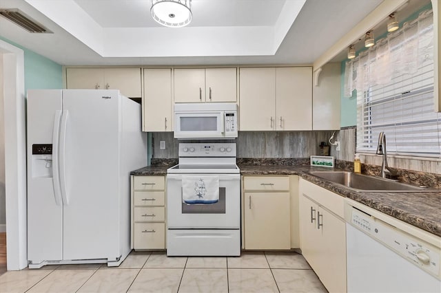 kitchen featuring a raised ceiling, cream cabinets, sink, and white appliances