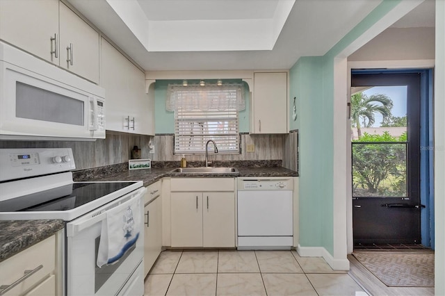 kitchen featuring dark stone countertops, white appliances, sink, and a healthy amount of sunlight