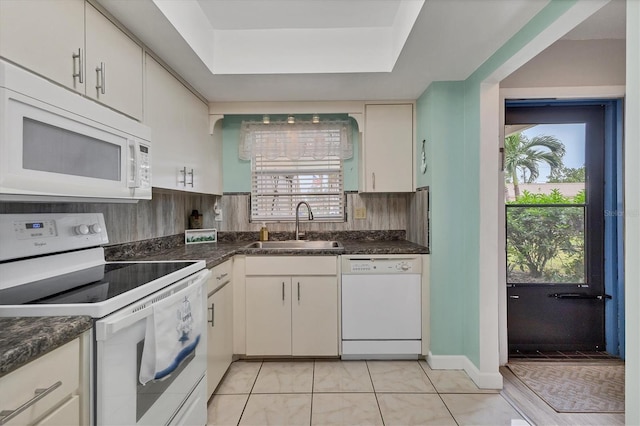 kitchen featuring white appliances, a sink, dark countertops, and light tile patterned floors