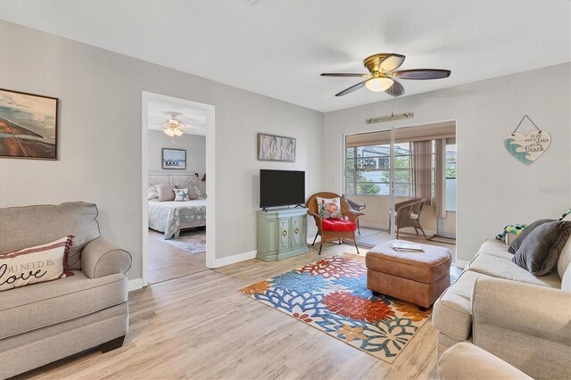 living room with ceiling fan, light wood finished floors, and baseboards