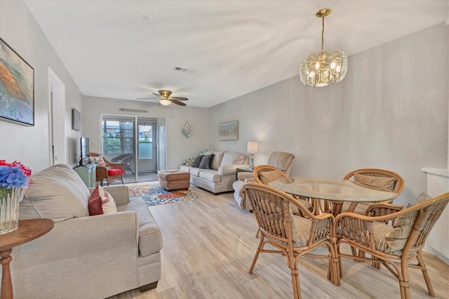 living room featuring ceiling fan with notable chandelier and light hardwood / wood-style flooring