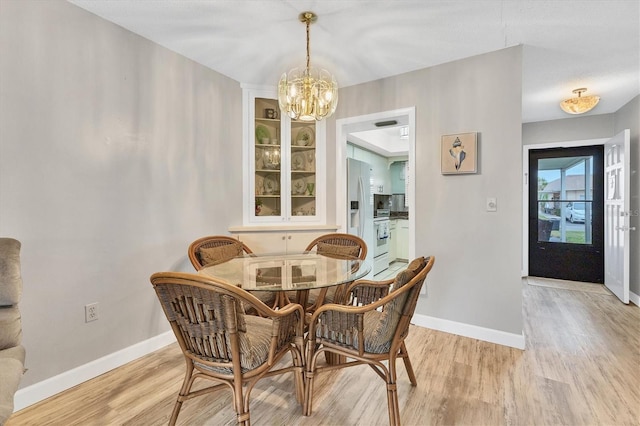dining room featuring light wood-type flooring, a chandelier, and baseboards