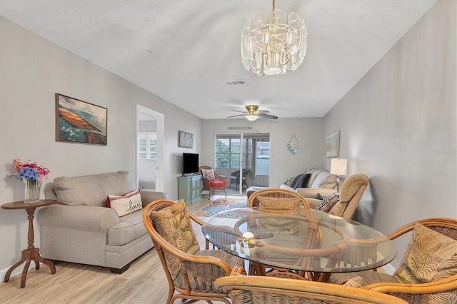 dining room featuring ceiling fan with notable chandelier and light hardwood / wood-style floors