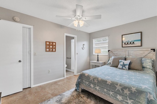 bedroom featuring light tile patterned flooring, baseboards, a ceiling fan, and connected bathroom