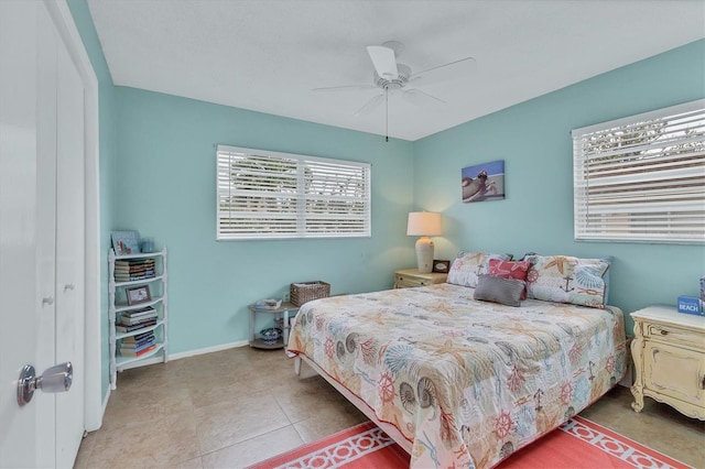 bedroom with ceiling fan, light tile patterned floors, and baseboards