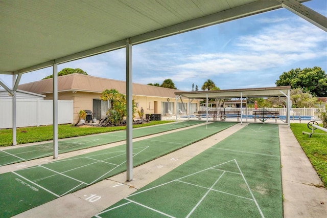 view of community with fence and shuffleboard