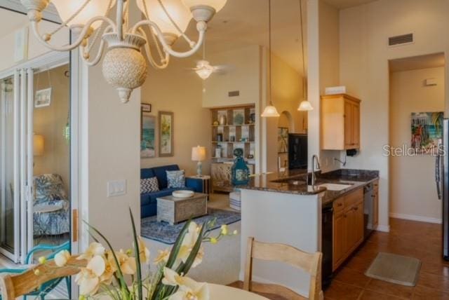 kitchen with white dishwasher, ceiling fan with notable chandelier, sink, tile patterned flooring, and kitchen peninsula