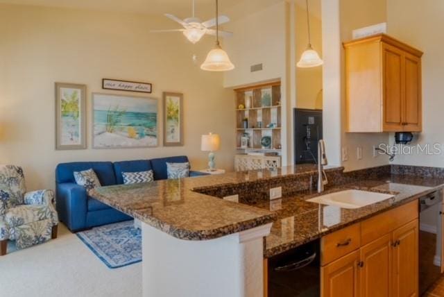 kitchen with dishwasher, a kitchen breakfast bar, dark stone counters, and sink