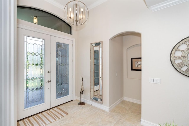 entryway with french doors, a notable chandelier, and crown molding