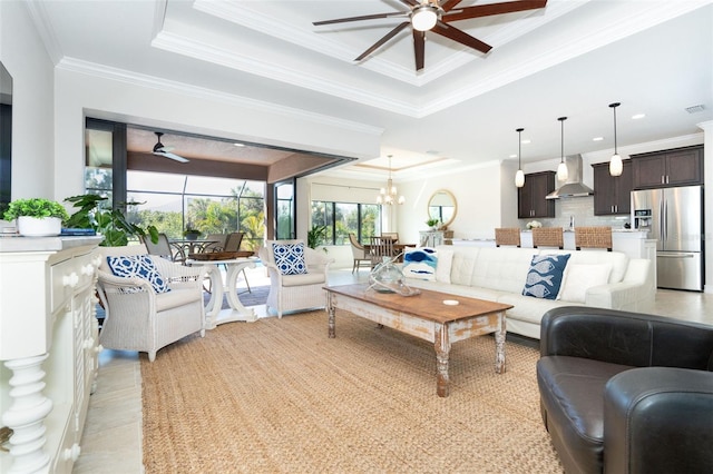 living room with light wood-type flooring, ceiling fan with notable chandelier, a raised ceiling, and crown molding