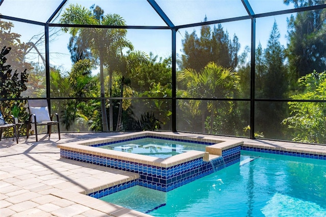 view of pool with glass enclosure, an in ground hot tub, and a patio area