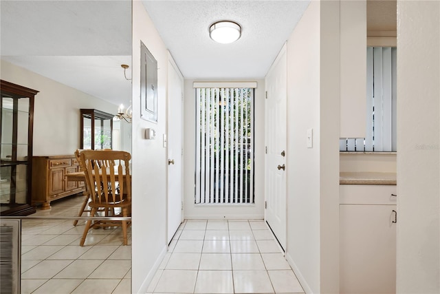 doorway to outside featuring a notable chandelier, light tile patterned floors, and a textured ceiling