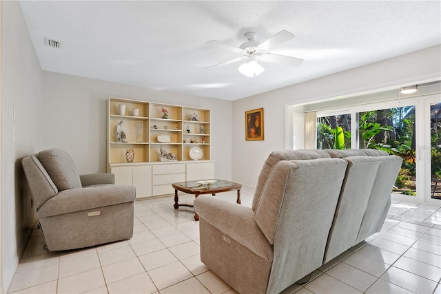 living room featuring light tile patterned flooring, ceiling fan, and a textured ceiling