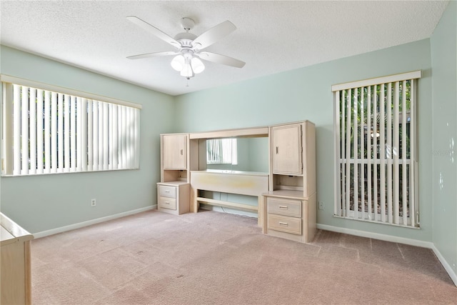 unfurnished bedroom featuring light carpet, a textured ceiling, and ceiling fan