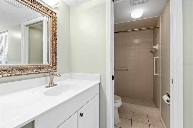 bathroom featuring vanity, tiled shower, toilet, tile patterned floors, and a textured ceiling