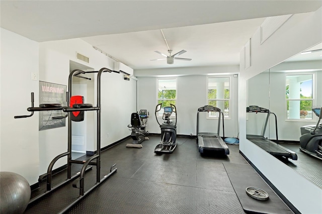 exercise room with a wall mounted AC, ceiling fan, and baseboards