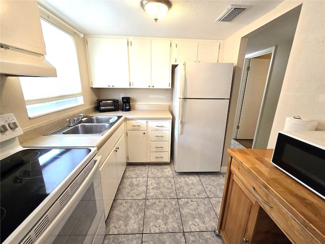 kitchen featuring light tile patterned flooring, stove, sink, and white refrigerator