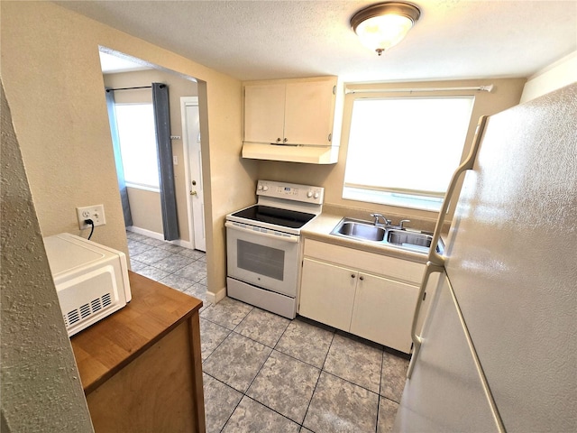 kitchen with exhaust hood, white appliances, sink, and a healthy amount of sunlight