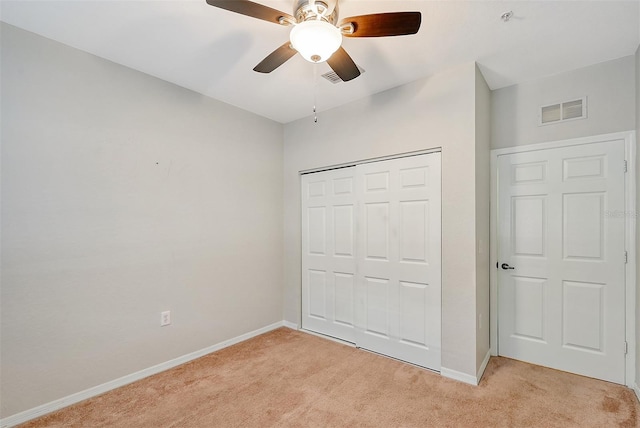 unfurnished bedroom featuring ceiling fan, a closet, and light carpet