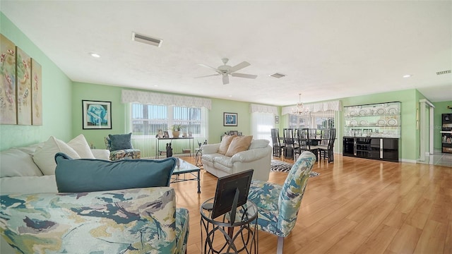 living room featuring light hardwood / wood-style floors and ceiling fan with notable chandelier