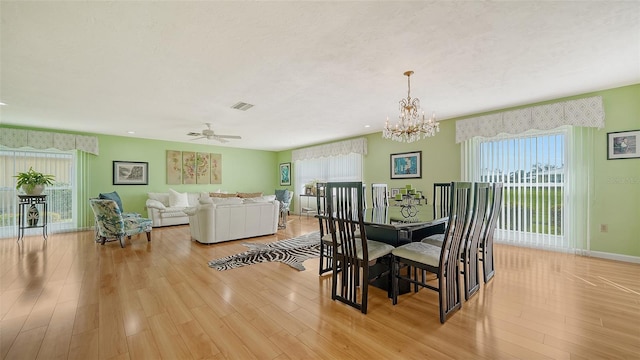 dining room with ceiling fan with notable chandelier and light hardwood / wood-style flooring