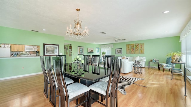 dining space featuring light hardwood / wood-style floors and ceiling fan with notable chandelier