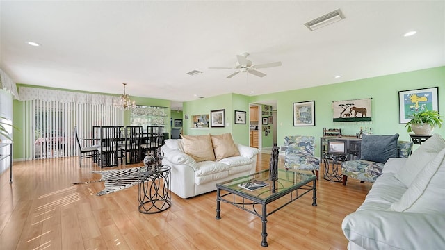 living room featuring light wood-type flooring and ceiling fan with notable chandelier