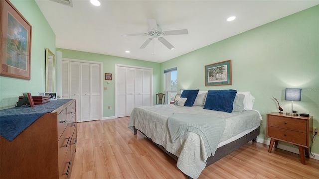 bedroom featuring light hardwood / wood-style floors, two closets, and ceiling fan