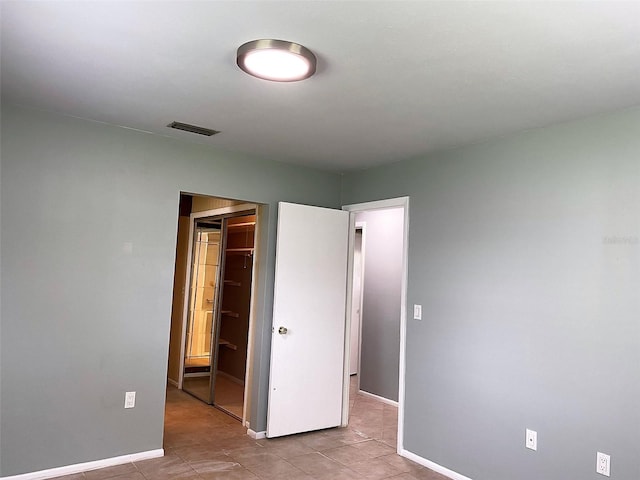 unfurnished bedroom featuring a spacious closet, light tile patterned floors, and a closet