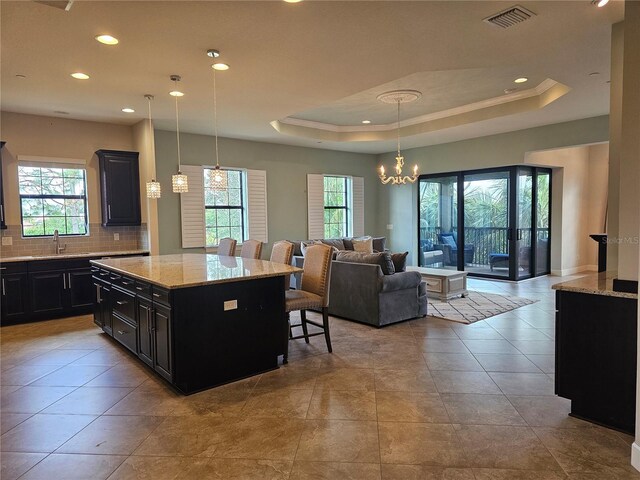 kitchen featuring a kitchen breakfast bar, pendant lighting, a kitchen island, and a healthy amount of sunlight