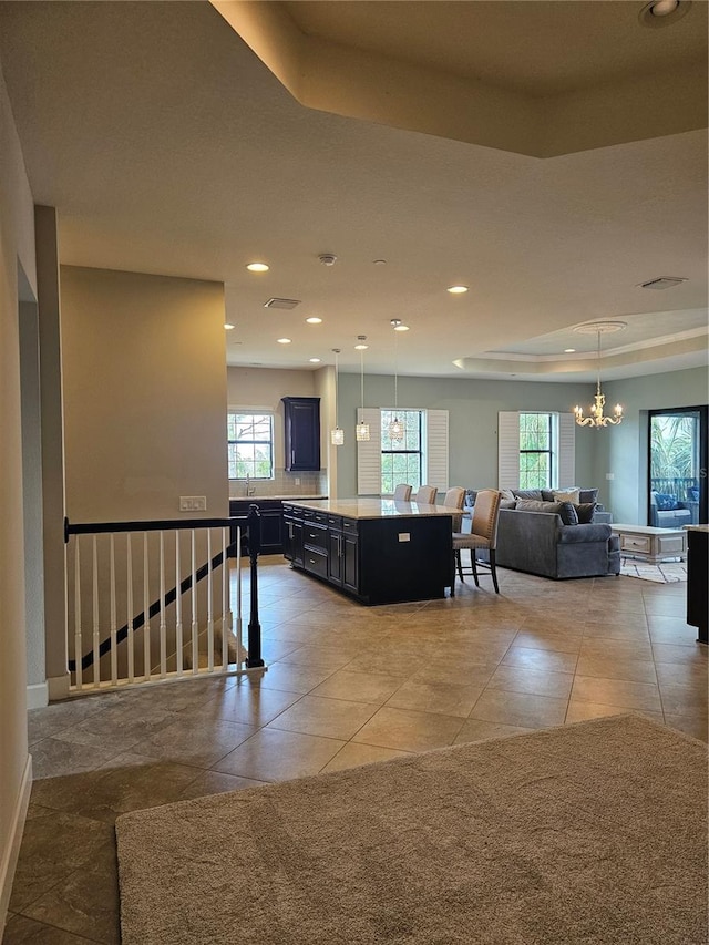 kitchen featuring a raised ceiling, a kitchen island, pendant lighting, and a kitchen breakfast bar